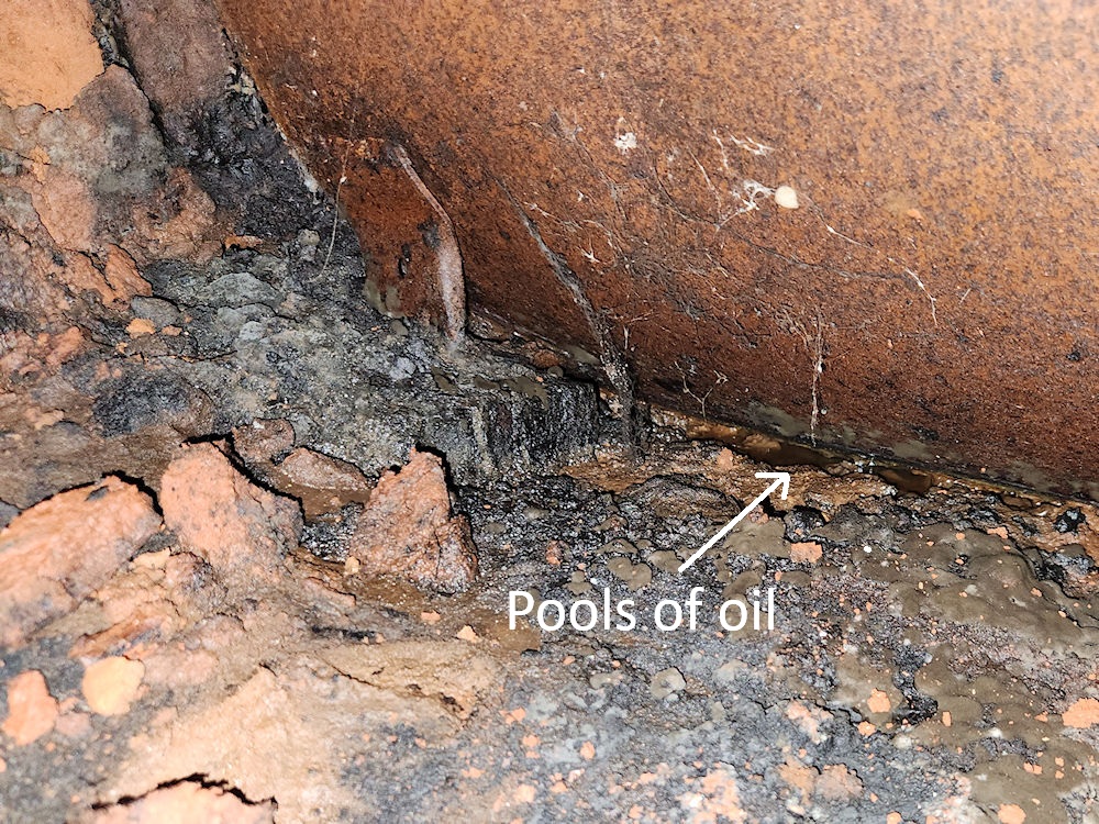 Aboveground tank in basement in contact with soils. Leaking oil is pooling on the soil beneath the tank Aboveground tank in basement in contact with soils. Leaking oil is pooling on the soil beneath the tank